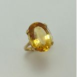 A CITRINE DRESS RING, with large oval shape faceted citrine to the plain tapered band, ring size I