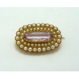 AN ANTIQUE EARLY 20TH CENTURY BROOCH, with central oval shape pink stone, within a double surround