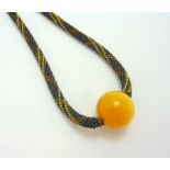A BUTTERSCOTCH AMBER BEAD NECKLACE, with singular large amber bead to the decorative beaded necklet,