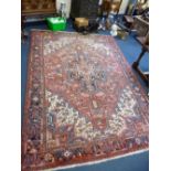 A RED GROUND WOOL CARPET, approximate size 330cm x 235cm