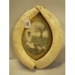 A 1920'S PHOTO FRAME, framed by two carved ivory tusks