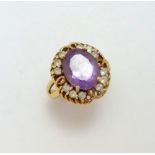 A 9CT GOLD AMETHYST AND CUBIC ZIRCONIA CLUSTER RING, with central oval shape amethyst within a