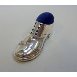 AN EDWARDIAN SILVER NOVELTY PIN CUSHION, modelled as a shoe, embossed decoration and wood sole, 12.