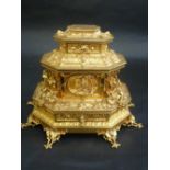 A LOUIS XV STYLE GILT METAL TABLE CASKET, of canted sarcophagus form, moulded in high relief with