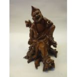 A CHINESE CARVED ROOTWOOD FIGURE OF ZHONGLI QUAN, modelled seated on a knotty tree stump, a small