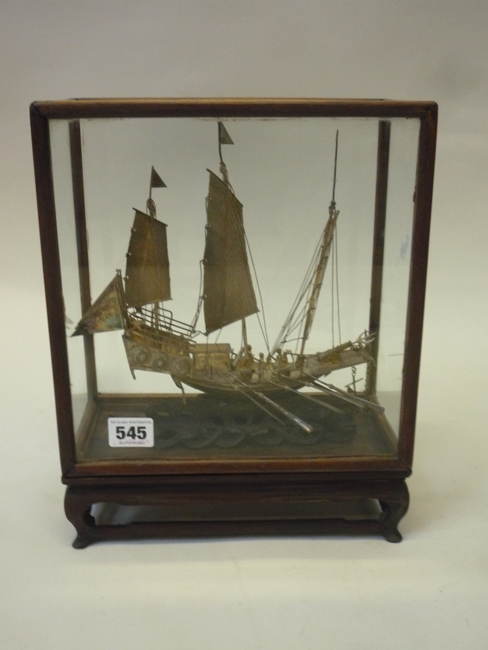 A CHINESE SILVER MODEL OF A WARSHIP, on carved wood base and glazed cabinet, 19th/20th Century