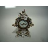 A CONTINENTAL FLORALLY ENCRUSTED PORCELAIN MANTEL CLOCK, rococo style case mounted with cherubs,