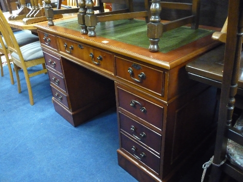 A YEW WOOD KNEE HOLE DESK, with eight drawers and green leather inlay top