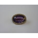 AN AMETHYST BROOCH, with oval shape amethyst within a surround and pearls, stamped 9ct