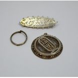 THREE ITEMS OF JEWELLERY, to include a filigree pendant, an engraved brooch and a band ring (s.d.)