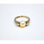 AN 18CT GOLD DIAMOND AND PEARL RING, the central pearl flanked by two brilliant cut diamonds to