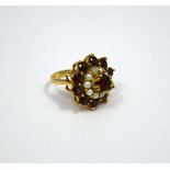 A 9CT GOLD DRESS RING, with central garnet within a surround of pearls to a further surround of