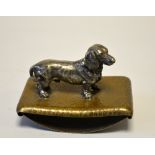 A SILVERED BRONZE FIGURE OF A DACHSHUND, mounted on a hammered copper blotter, height