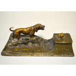 A FRENCH BRONZE INKWELL AND PEN REST, modelled as a Dachshund barking at a chick stood on the hinged
