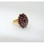 A 9CT GOLD GARNET CLUSTER RING, with central oval garnet within a double surround of further