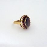 A 9CT GOLD GARNET CLUSTER RING, with large central oval garnet to a surround of smaller circular