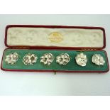 A SET OF SILVER BOXED BUTTONS, designed as opening flowers, two of the buttons have been converted