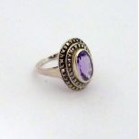 AN AMETHYST AND MARCASITE DRESS RING, with faceted central oval amethyst within two surrounds of