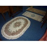 A CHINESE FAWN GROUND RUG, approximate size 155cm x 75cm, an oval oatmeal ground rug, another rug