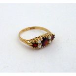 A 9CT GOLD GARNET AND PEARL RING, with three graduated garnets and pearl accents to a scrolling
