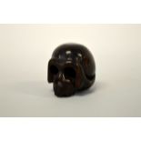 A JAPANESE CARVED WOOD NETSUKE, in the form of a skull, signed on ivory to base