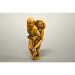 A JAPANESE IVORY NETSUKE, figure of an old man carrying an old lady who is holding a fish