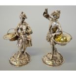 A PAIR OF VICTORIAN SILVER SALTS, each well cast as a gentleman and lady dressed in clothes out on a