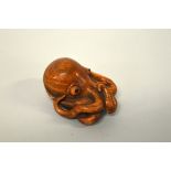 A JAPANESE BOXWOOD NETSUKE, of an Octopus, the eyes inlaid, signed to rear