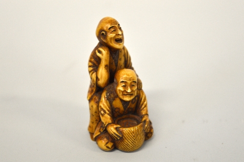 A JAPANESE BOXWOOD NETSUKE, carved as men at work, signed to base