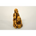 A JAPANESE BOXWOOD NETSUKE, carved as men at work, signed to base