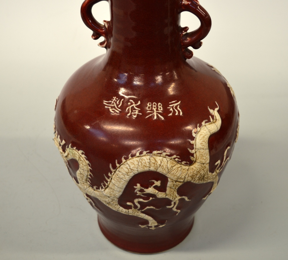 AN ORIENTAL RED GROUND VASE, with dragon and flower decoration in relief, four character script to - Image 2 of 2