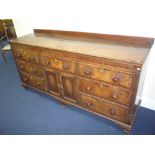 A GEORGIAN OAK AND MAHOGANY CROSSBANDED DRESSER BASE, with seven drawers, central cupboard with