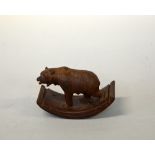 A BLACK FOREST CARVED BEAR, mounted on a wooden desk blotter, approximate length 13.5cm