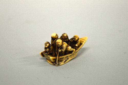 A JAPANESE IVORY NETSUKE, of five men in a boat, signed to base