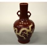AN ORIENTAL RED GROUND VASE, with dragon and flower decoration in relief, four character script to