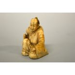 A JAPANESE IVORY NETSUKE, figure of a man kneeling with an axe, signed to base