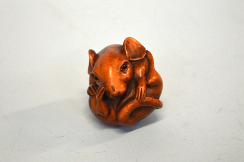 A JAPANESE BOXWOOD NETSUKE, of a Rat, curled into a ball, the eyes inlaid, signed to the base