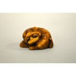 A JAPANESE IVORY NETSUKE, carved in the form of a pug curled up, the eyes inlaid, signed to base