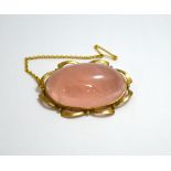 A ROSE QUARTZ BROOCH, of oval cabouchon design within a yellow metal scalloped border, with safety