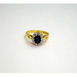 AN 18CT GOLD SAPPHIRE AND DIAMOND RING, with central oval sapphire within a surround and diamonds to
