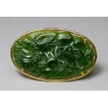 An 18ct gold mounted carved jade brooch, the jade plaque carved with birds amongst foliage, in plain