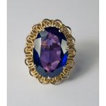 A synthetic Alexandrite dress ring, the oval cut stone set in high ct yellow metal, an entwined