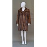 A demi-buff mink coat, with small collar and concealed fastenings, full three-quarter length sleeves