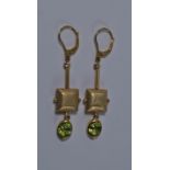 A pair of gold, peridot and diamond set earrings, the textured cushion form below tubular bar set