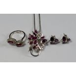 An 18ct white gold, ruby and diamond set parure, comprising spray form brooch/pendant on chain, ring