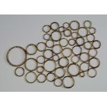 A collection of unmarked yellow metal split rings, of various sizes,