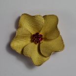 An 18ct gold and ruby flower head brooch, the petals with knurled finish and ruby set stamens,