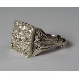 A platinum and diamond set plaque ring, the square pave set plaque in high pierced scrollwork mount,