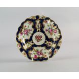 A Worcester porcelain plate, 18th century, with shaped rim, painted and gilt with shaped reserves of