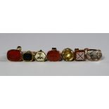 A collection of seven miniature yellow and gilt metal carved intaglio fob seals,